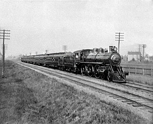 A steam powered train from the early 20th century, moving from left to right across the image.