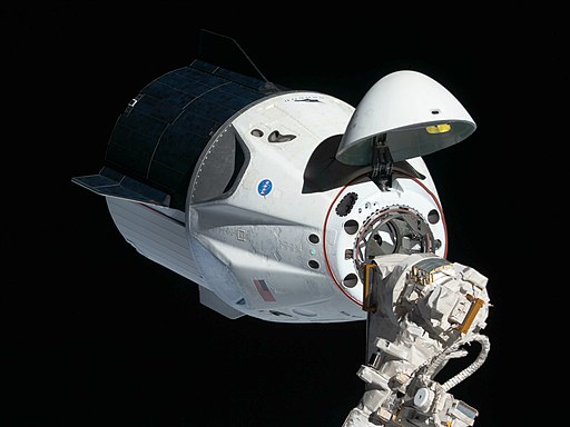Image of the SpaceX white space craft docking with the ISS. The nose cone has opened to reveal docking port.