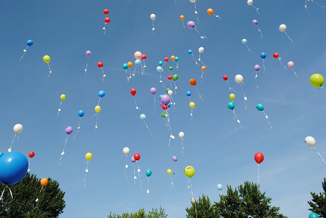 Image of a multi colored balloon release into a blue sky